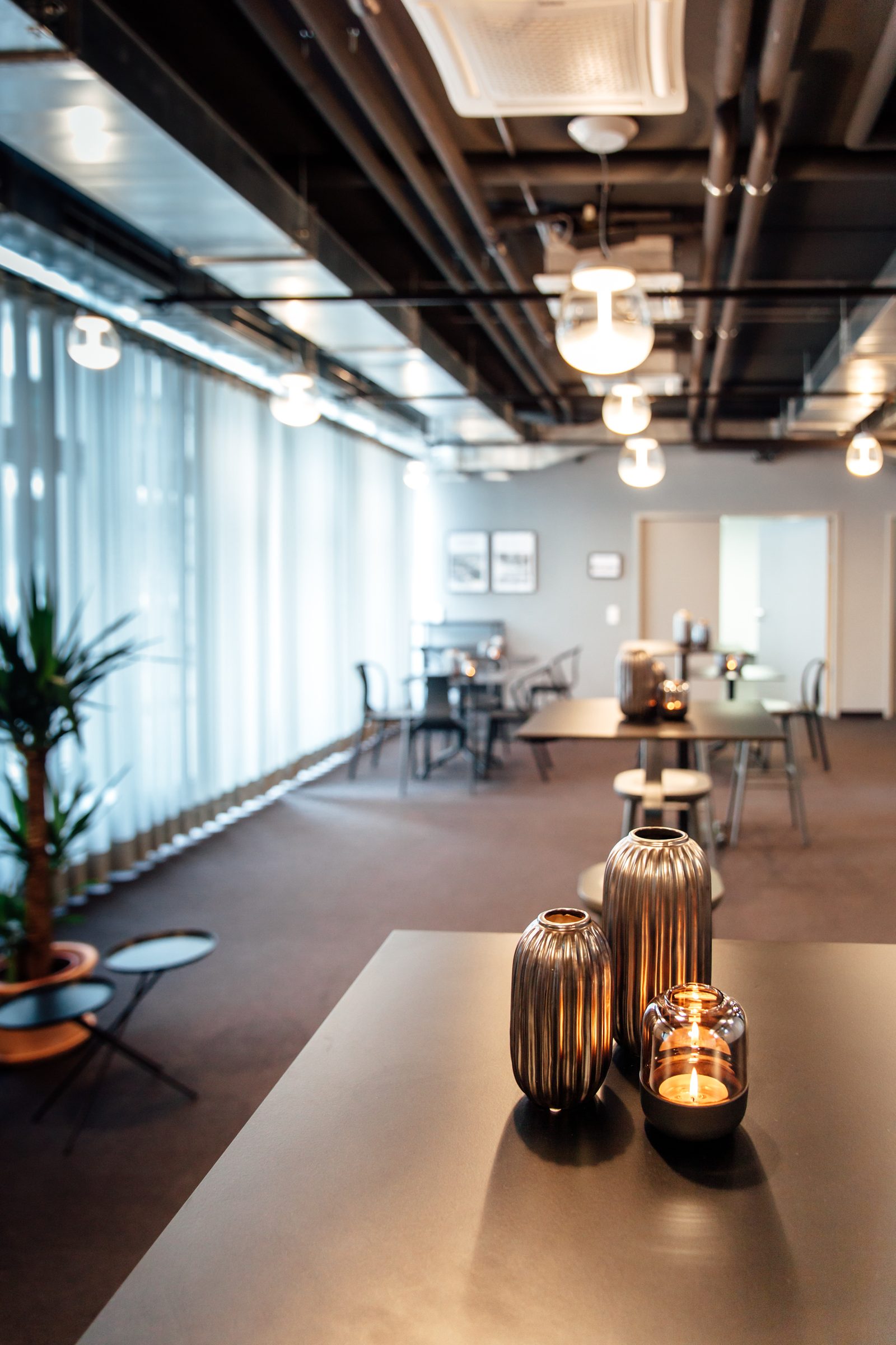 Tisch mit Windlichtern an der Fensterfront der Lounge, darüber Pendelleuchten von Artemide, Design Offices Stuttgart