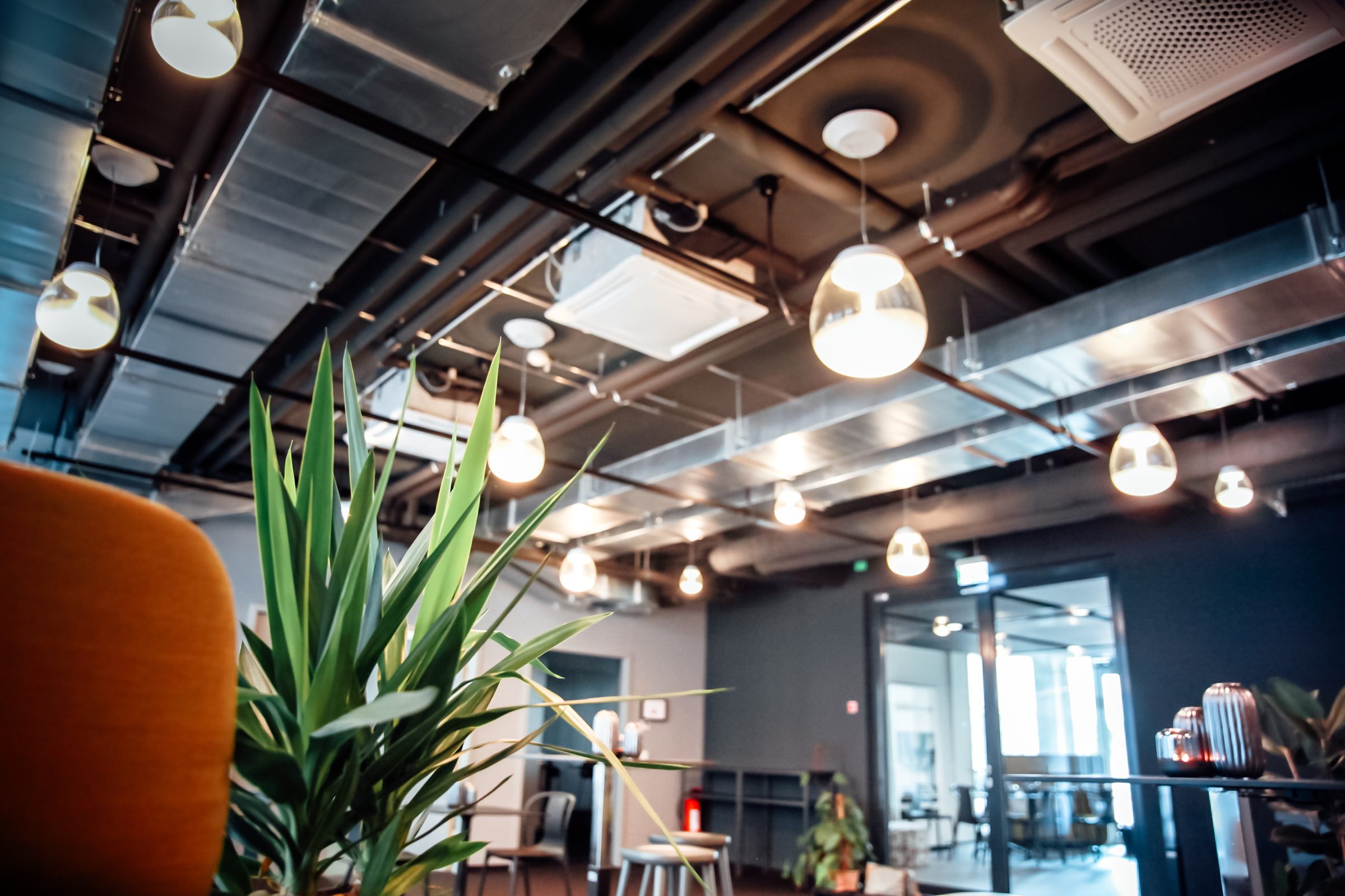 Blick unter die Decke mit Pendelleuchten von Artemide, im Vordergrund eine Pflanze und ein gelber Sessel, Design Offices Stuttgart