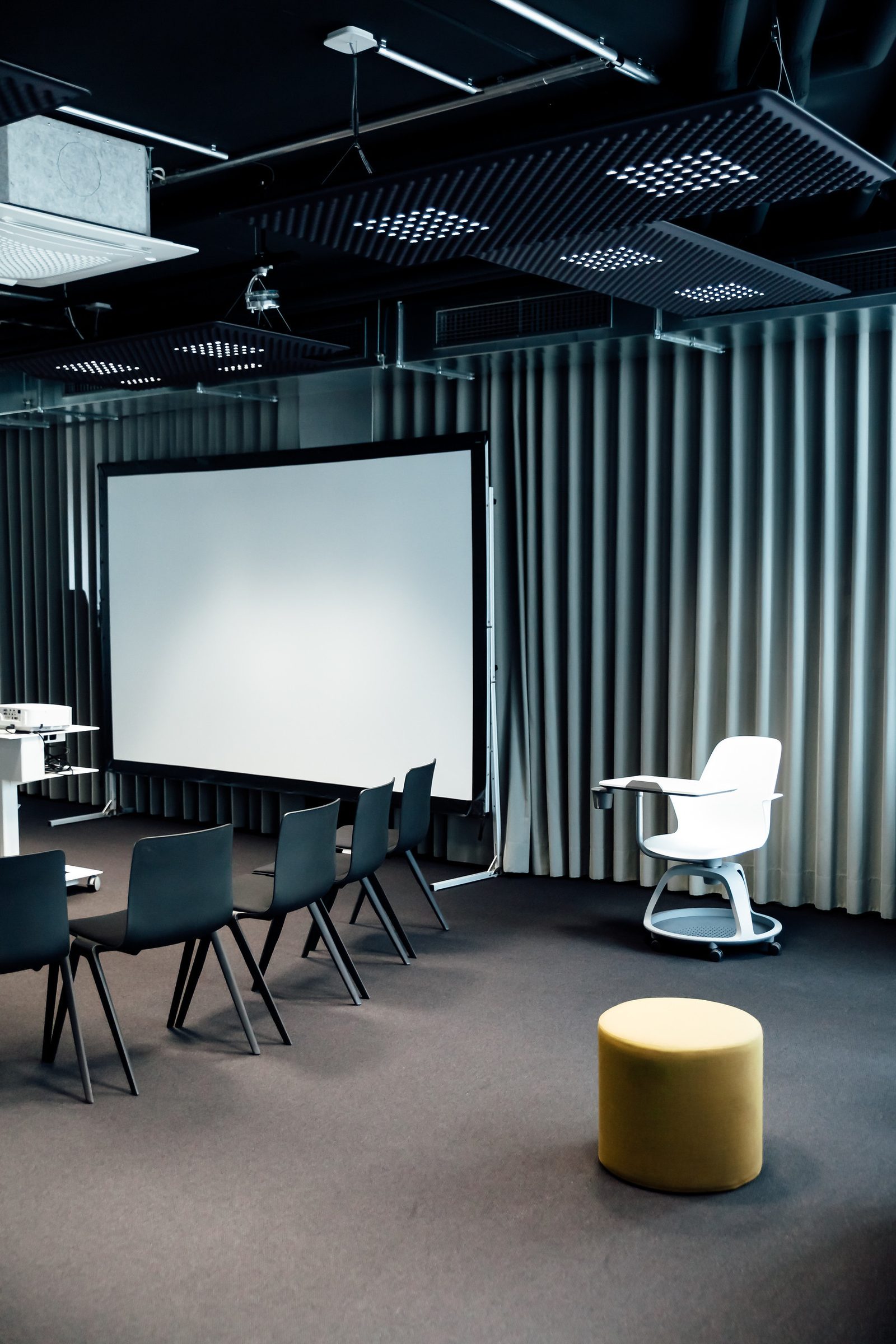 Leinwand, Stühle, weißer Drehstuhl und gelber Hocker im Konferenzraum der Design Offices Stuttgart