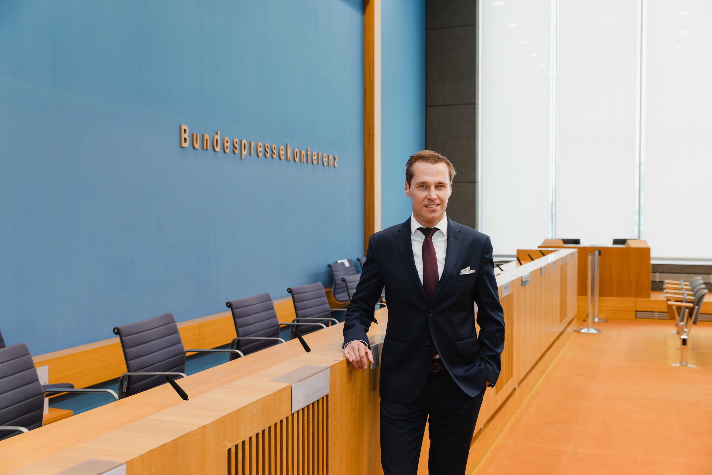 Mann im Anzug lehnt am Podium im Saal der Bundespressekonferenz