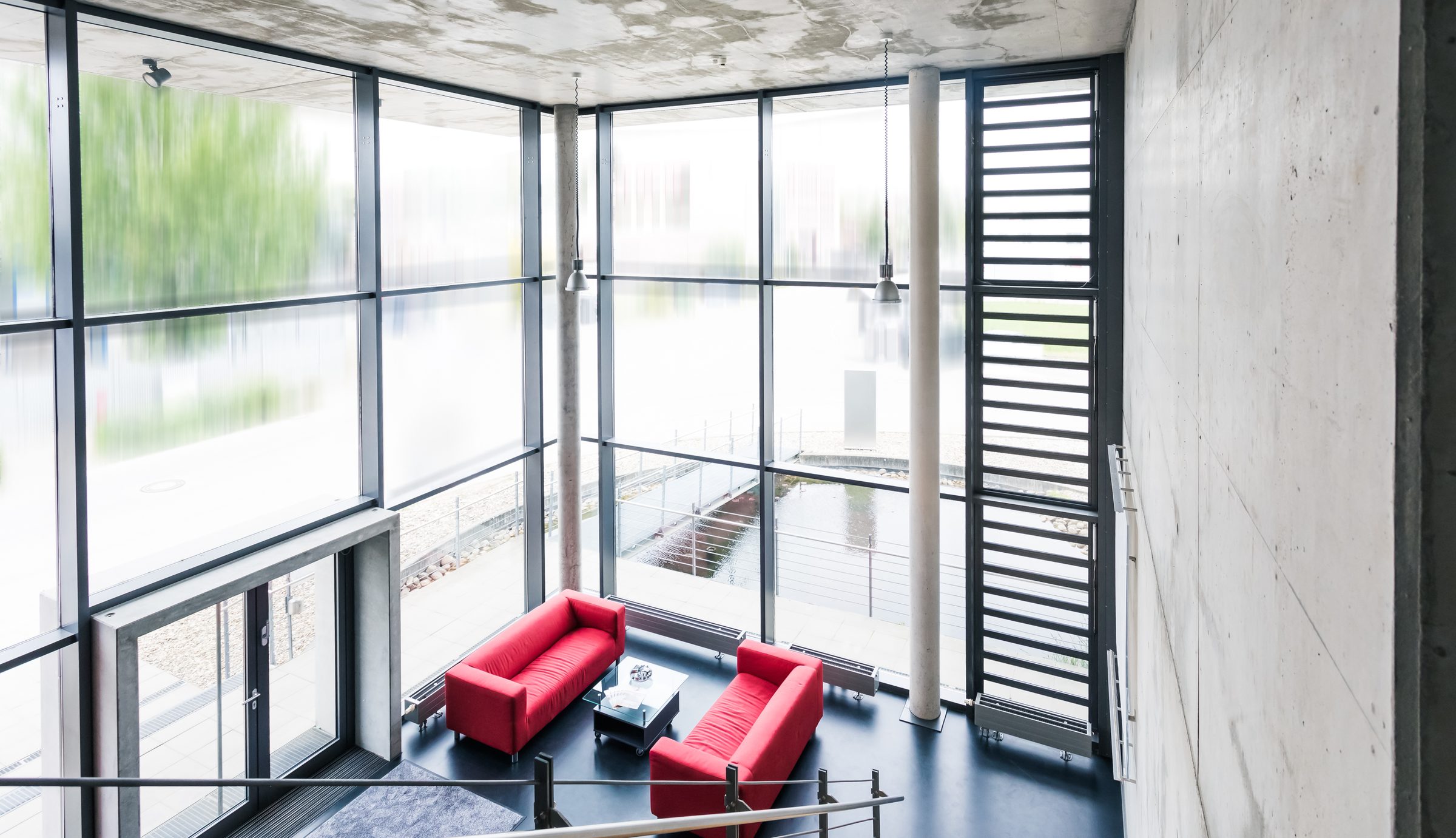Foyer von Eugen Geyer von oben mit zwei roten Sofas vor einer raumhohen Glasfassade
