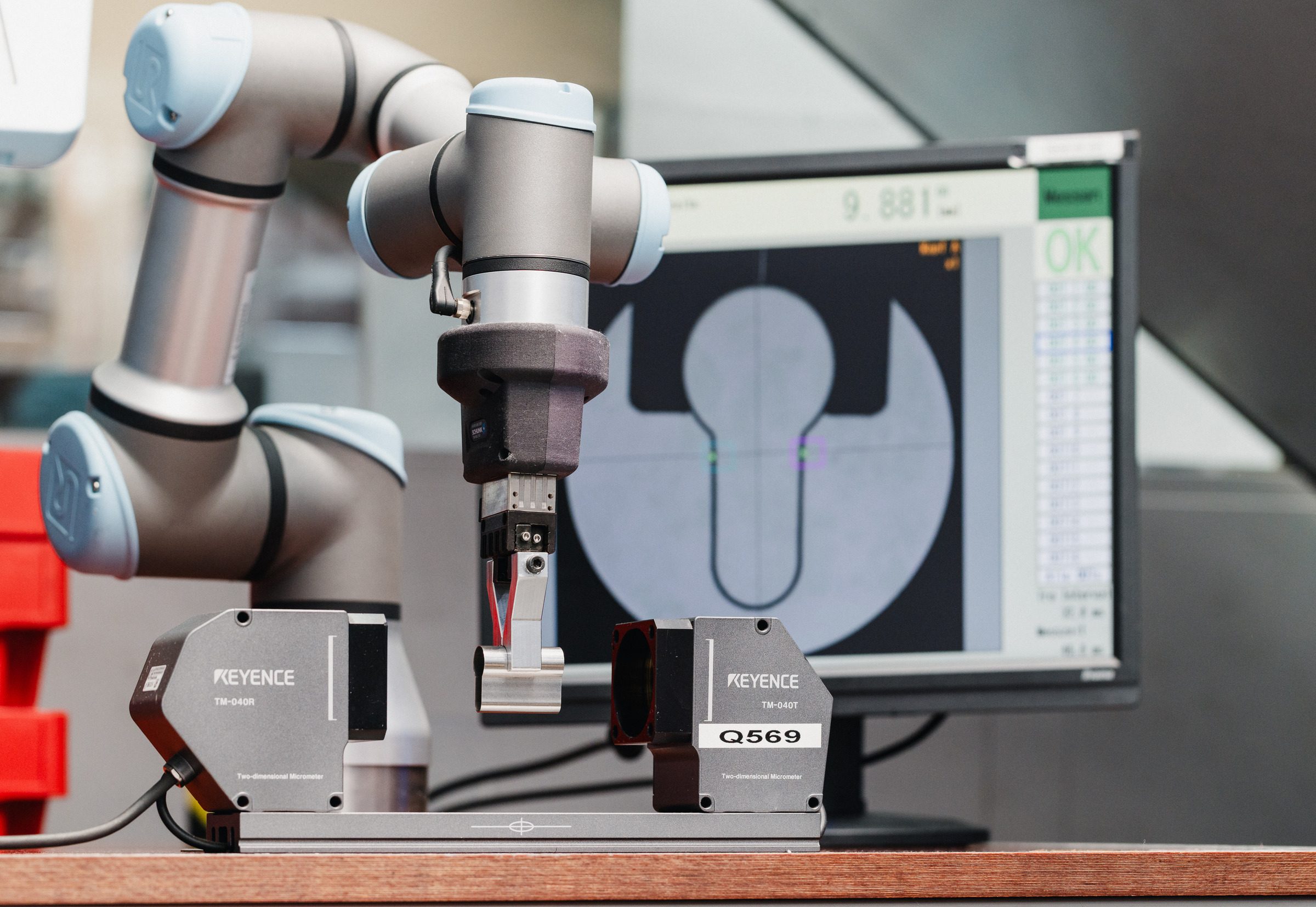 Roboterarm an einer optischen Messstation, auf dem Monitor der vermessene Profilquerschnitt, Qualitätskontrolle bei Eugen Geyer