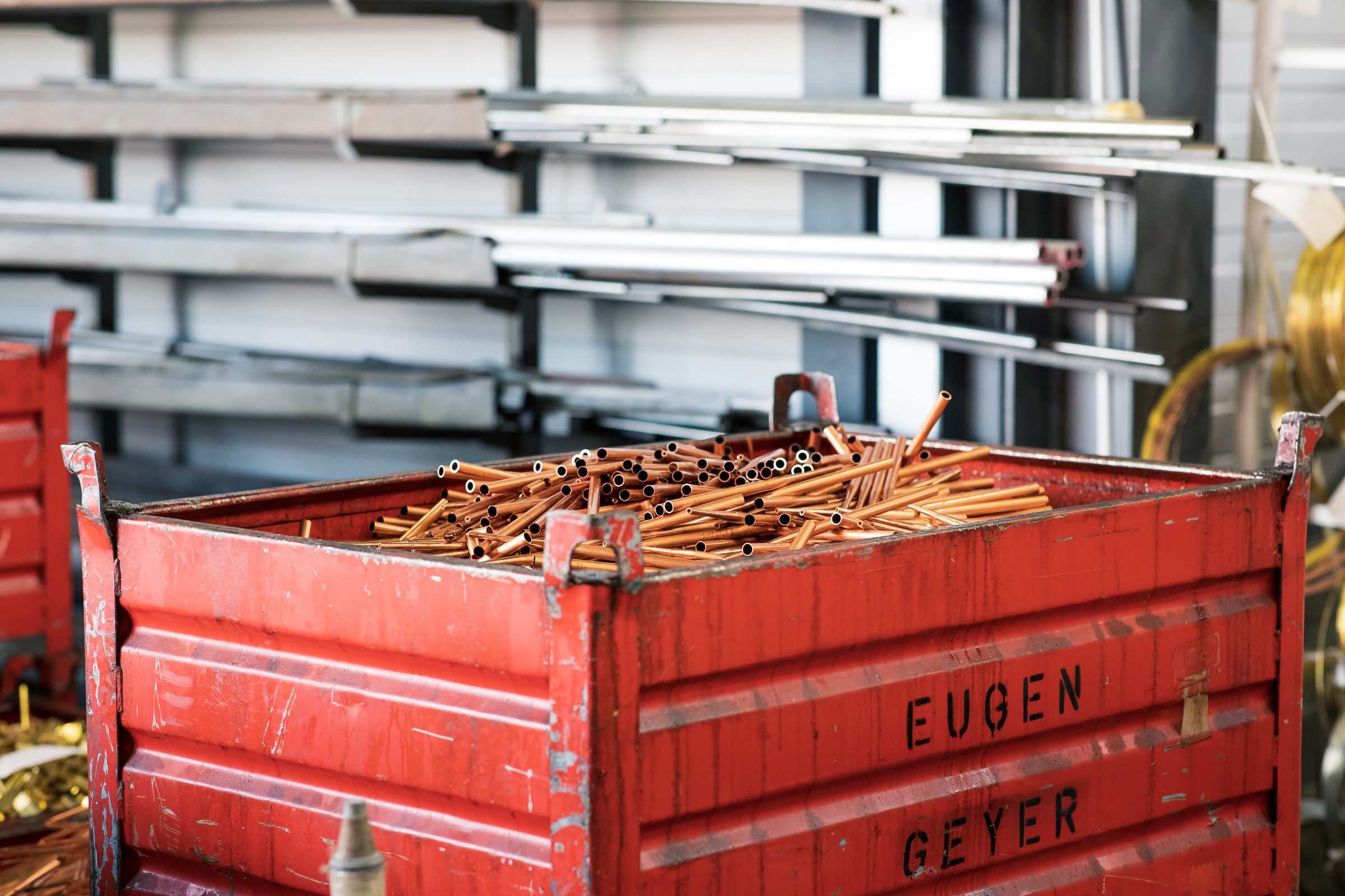 Roter Gitterbehälter mit der Aufschrift Eugen Geyer voller Kupferrohr-Reste für das Recycling