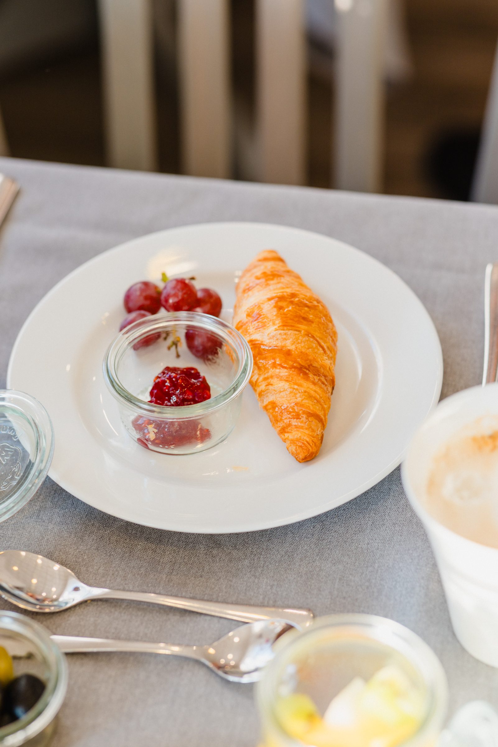 Teller mit Croissant, Trauben und Marmelade im Glas beim Frühstück im Hotel Engelhorn