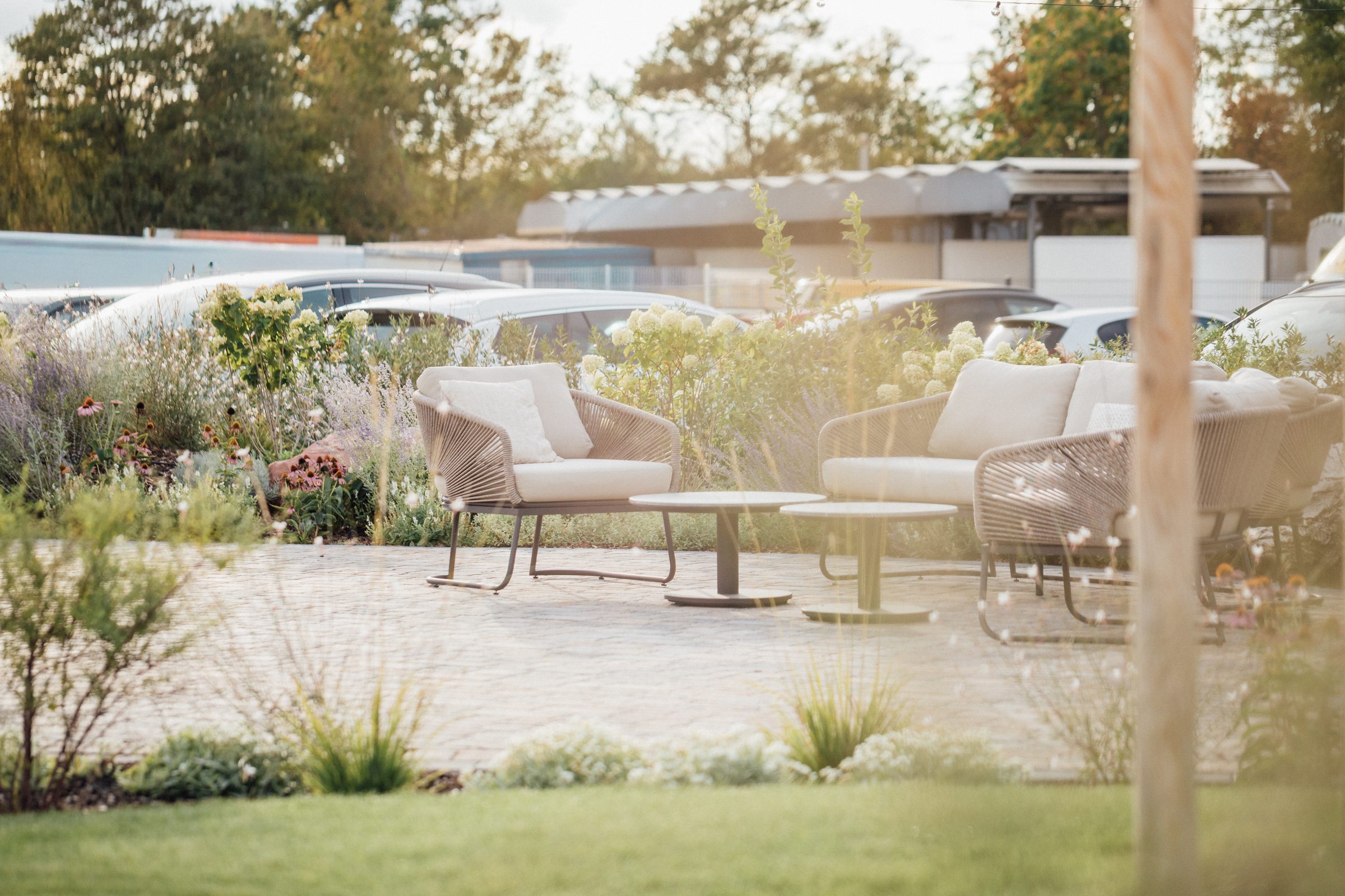 Lounge mit hellen Sesseln und Tischen auf einer Terrasse zwischen Gräsern und Blumen im Garten des Eventum beim Hotel Engelhorn