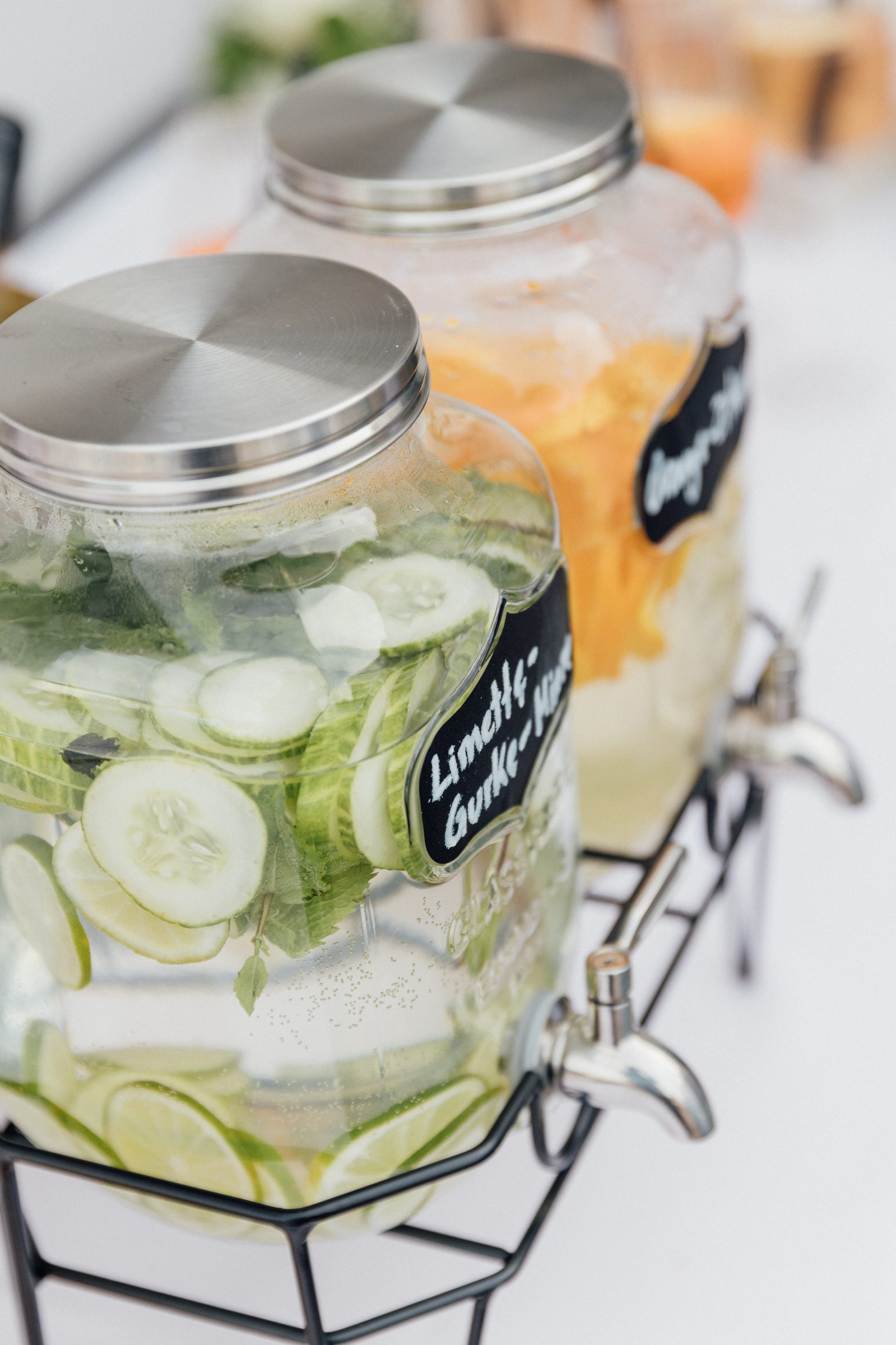 Getränkespender mit Gurken-Limetten-Wasser und Orangenwasser auf einem weißen Tisch im Hotel Engelhorn
