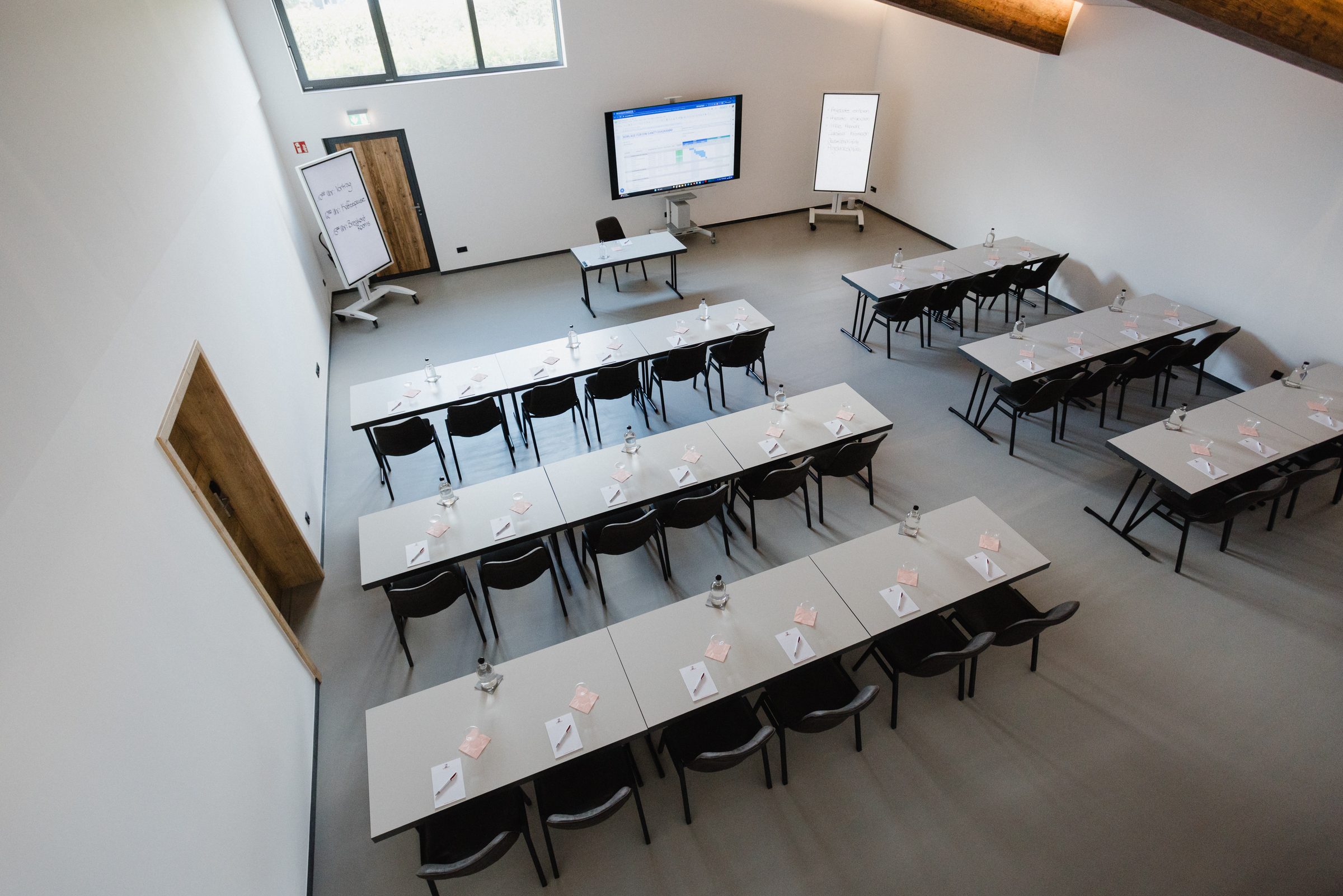 Seminarraum im Eventum des Hotel Engelhorn von oben mit Tischreihen, Bildschirm und Flipcharts