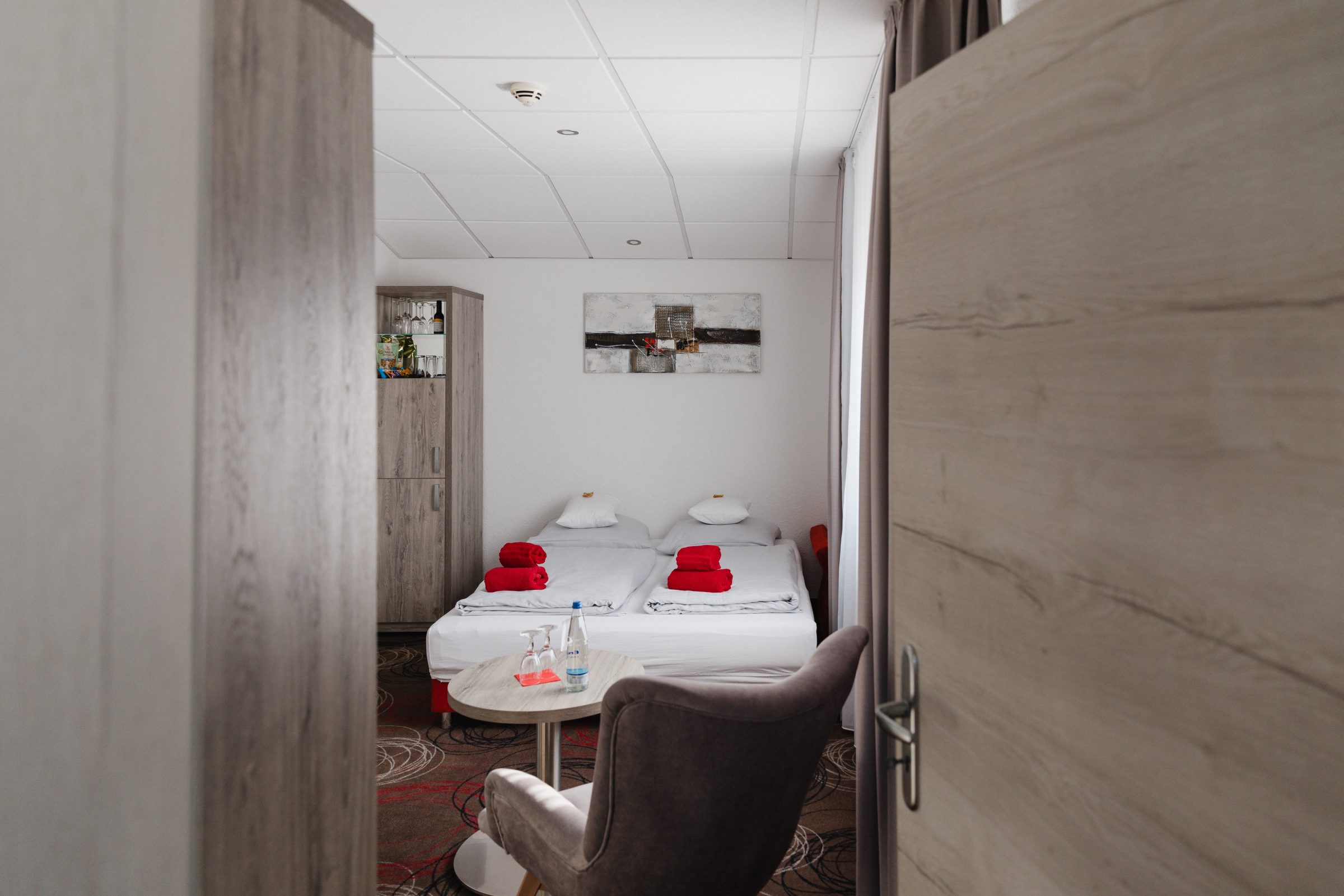 Blick durch die geöffnete Tür in ein Doppelzimmer des Hotel Engelhorn mit roten Handtüchern auf dem Bett
