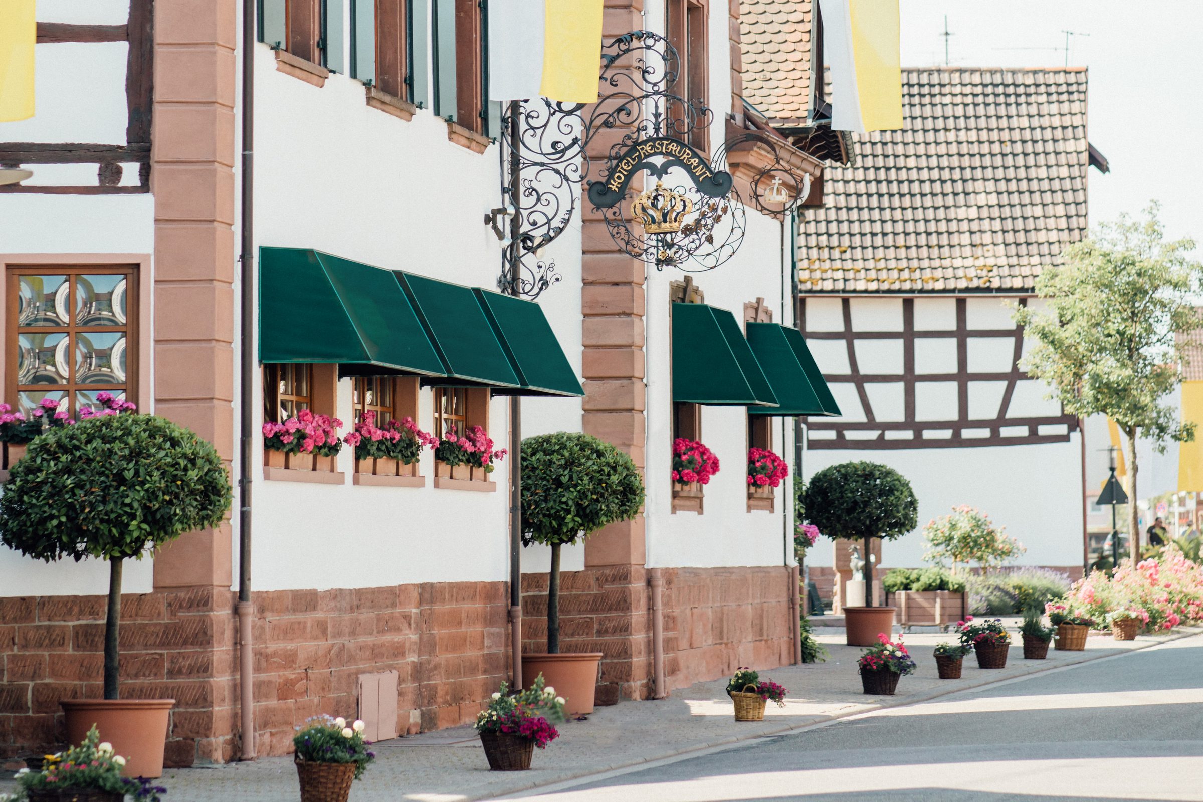 Außenansicht des Hotel Krone mit grünen Markisen, Blumenkästen und Fachwerkhäusern an der Straße