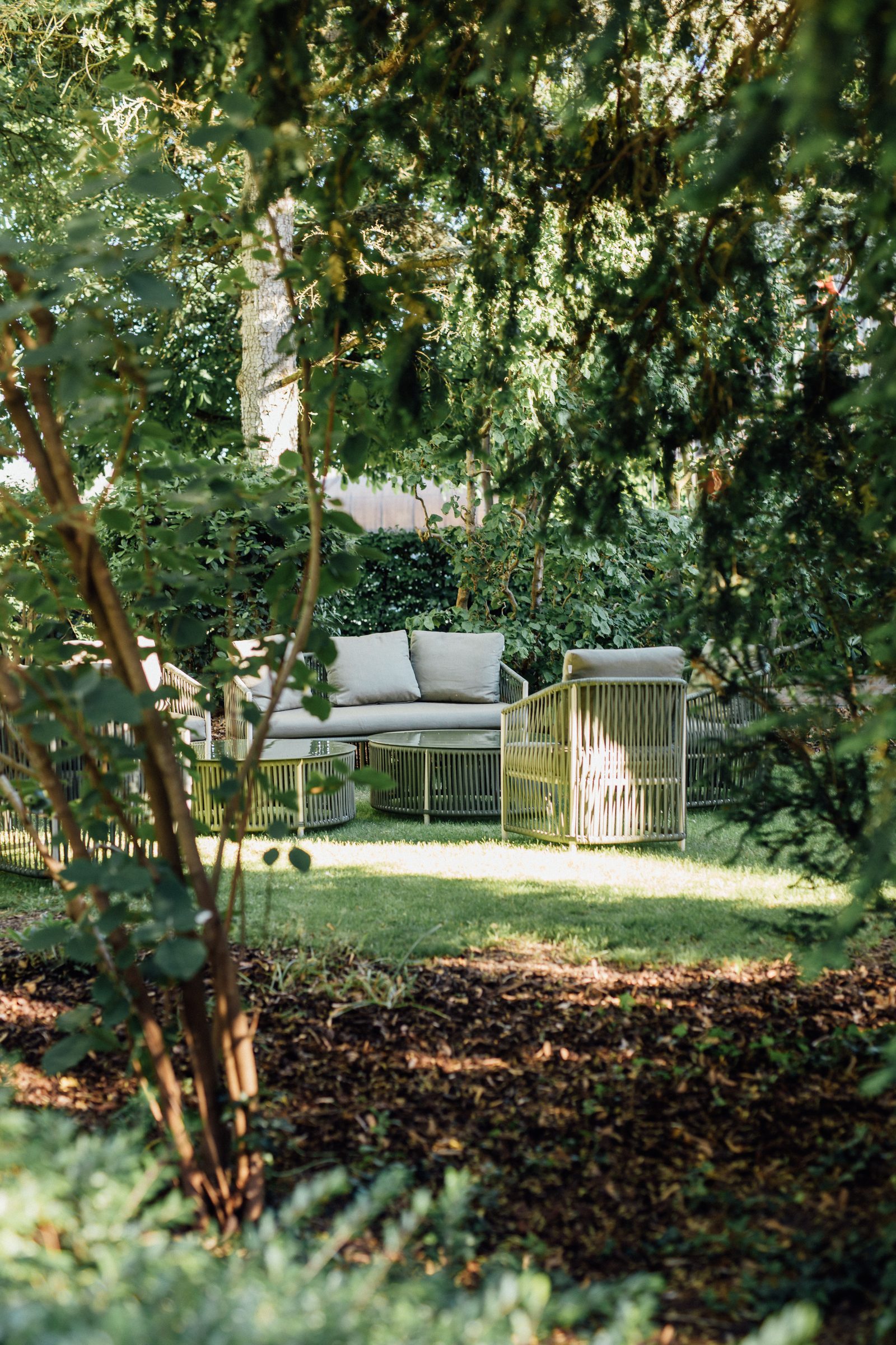 Lounge-Sitzgruppe auf dem Rasen im schattigen Garten des Hotel Krone