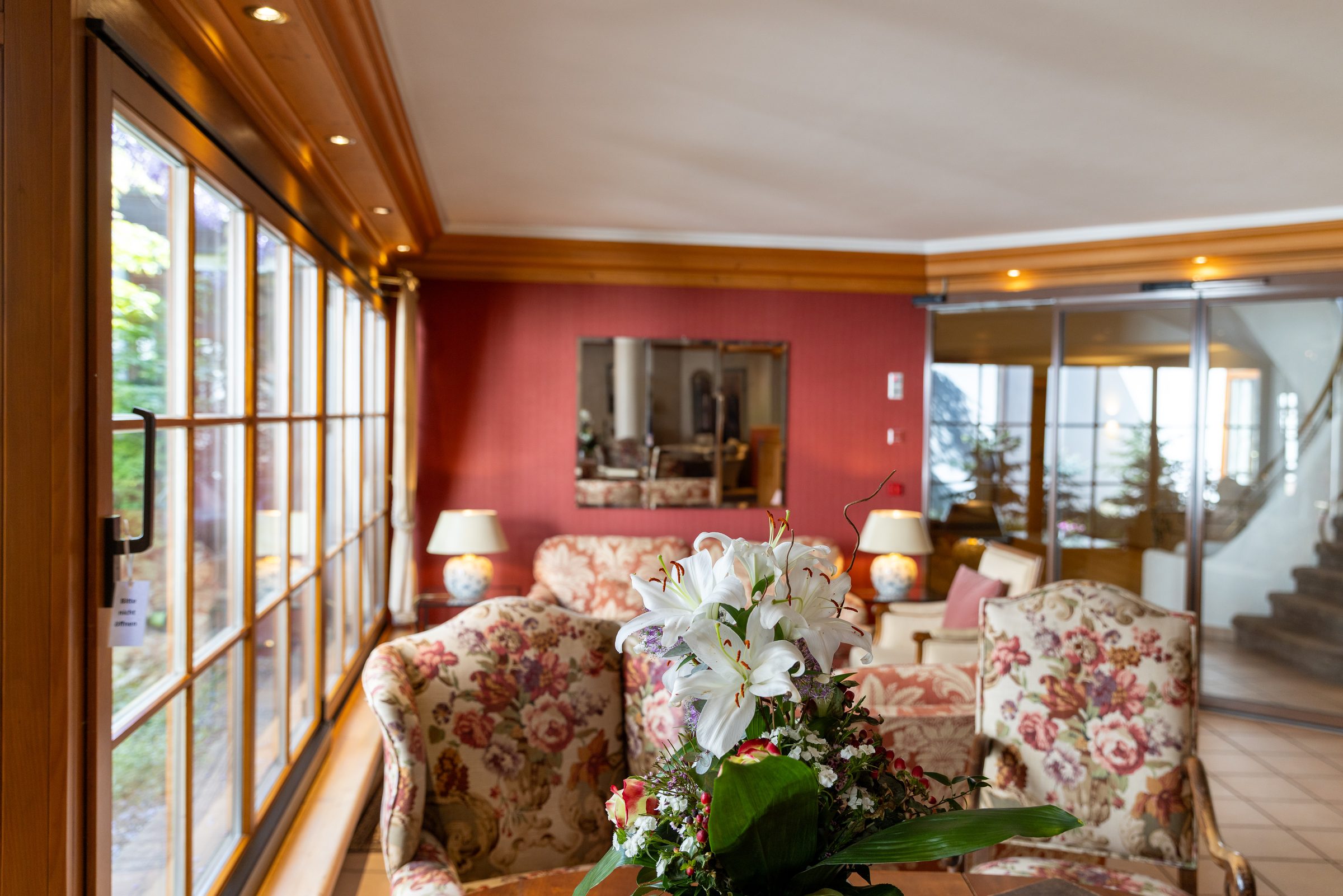 Sitzecke in der Lobby des Hotel Krone mit geblümten Sesseln, weißen Lilien und einer langen Fensterfront