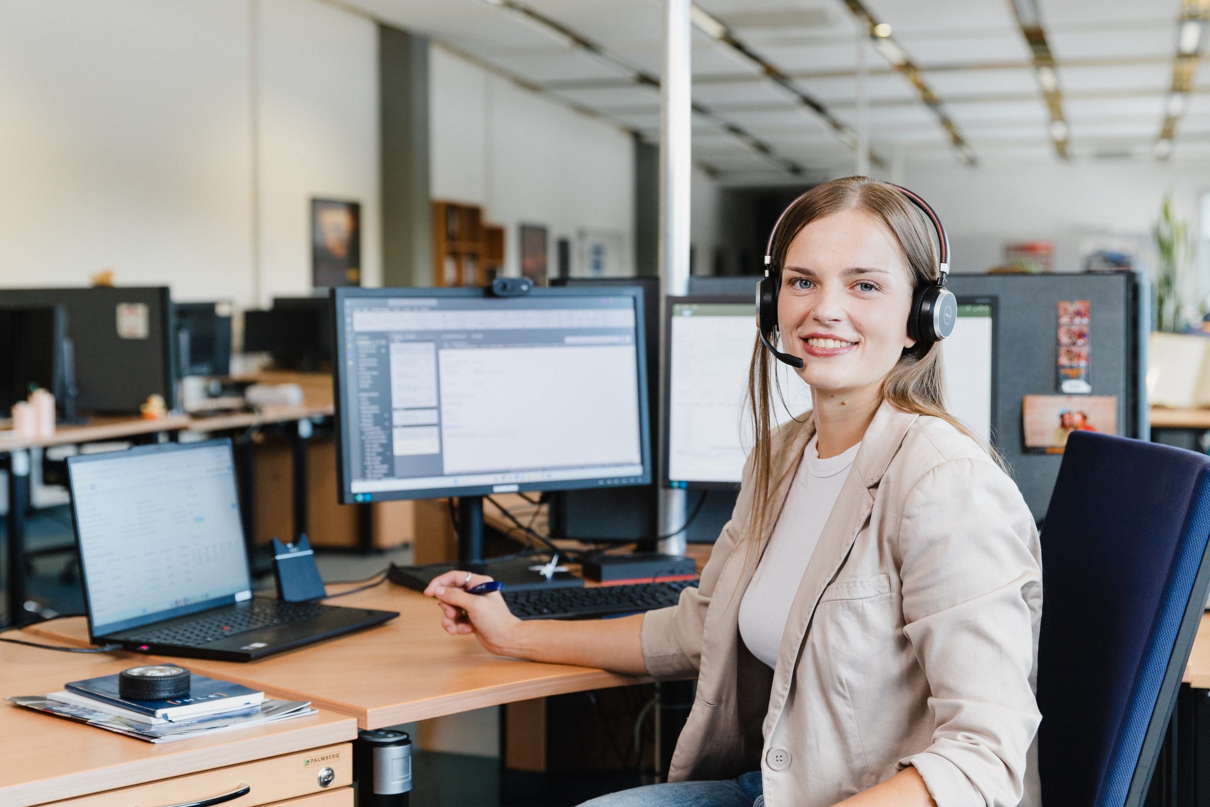 Mitarbeiterin mit Headset an ihrem Arbeitsplatz im Büro von IHLE