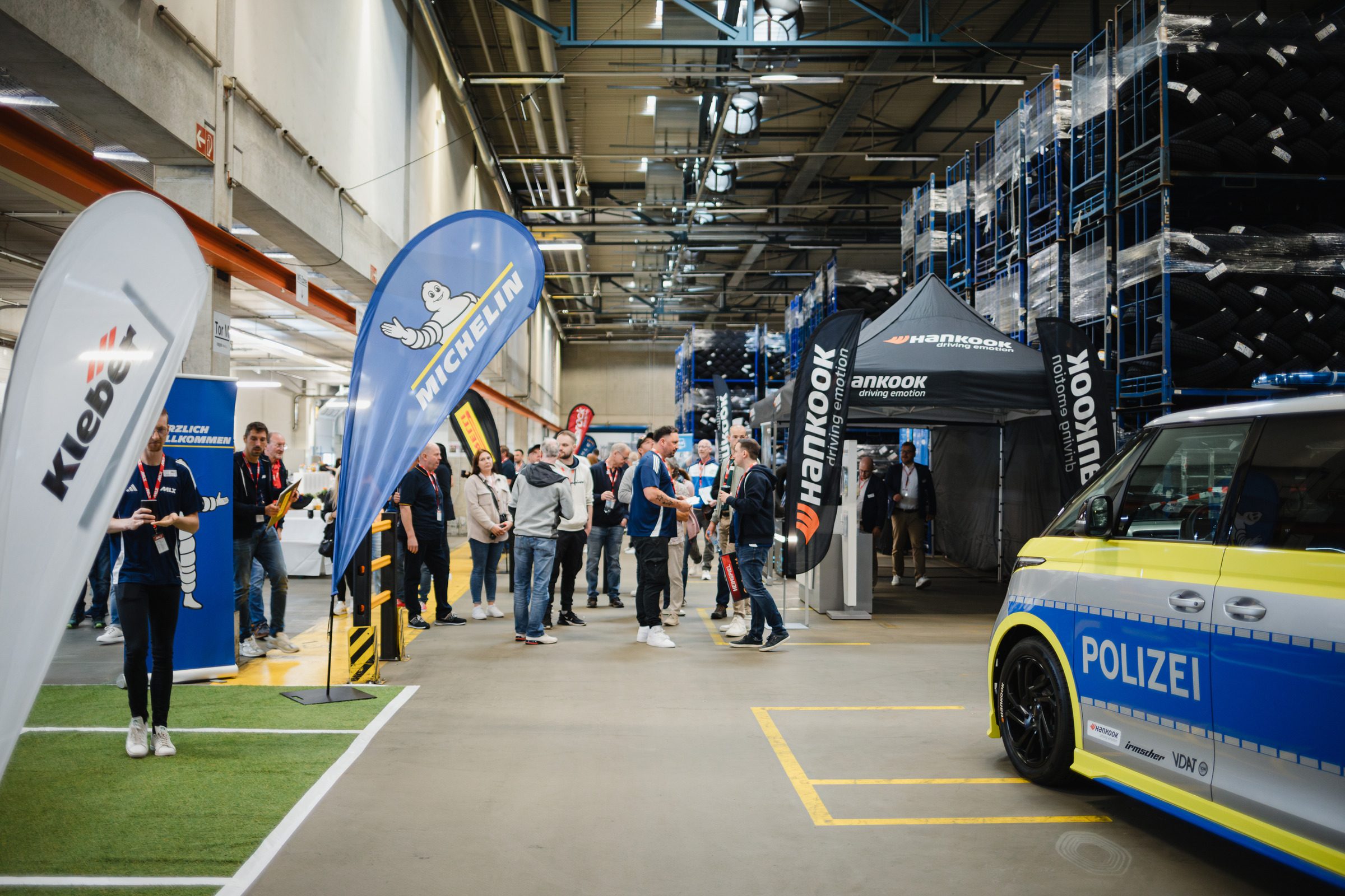 Ausstellerstände mit Beachflags und ein Polizeiauto in der Lagerhalle bei der Tagung von IHLE