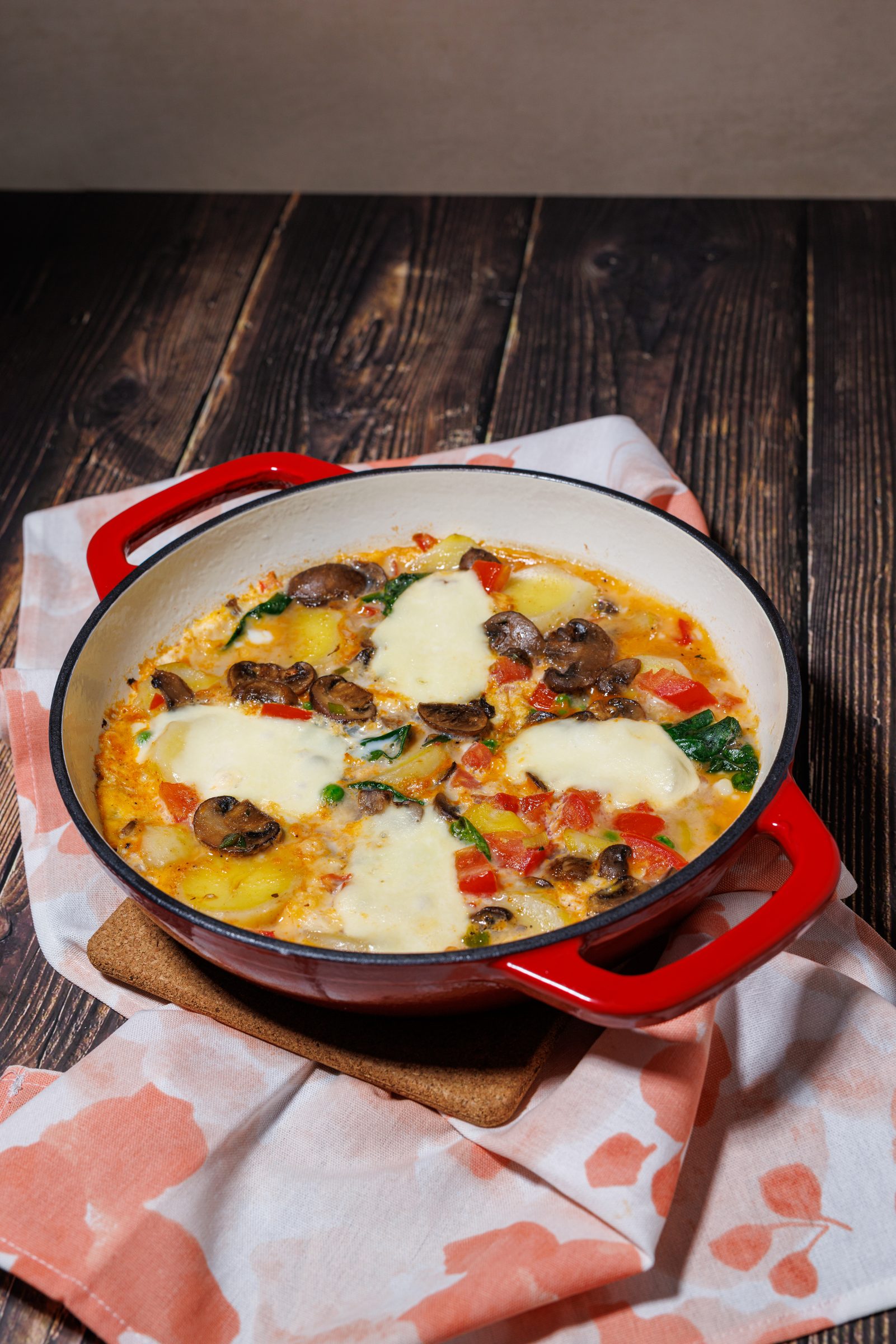 Gemüse-Frittata mit Pilzen, Paprika und Mozzarella in einer roten Pfanne auf dunklem Holz, Rezeptfoto für ein GU-Kochbuch