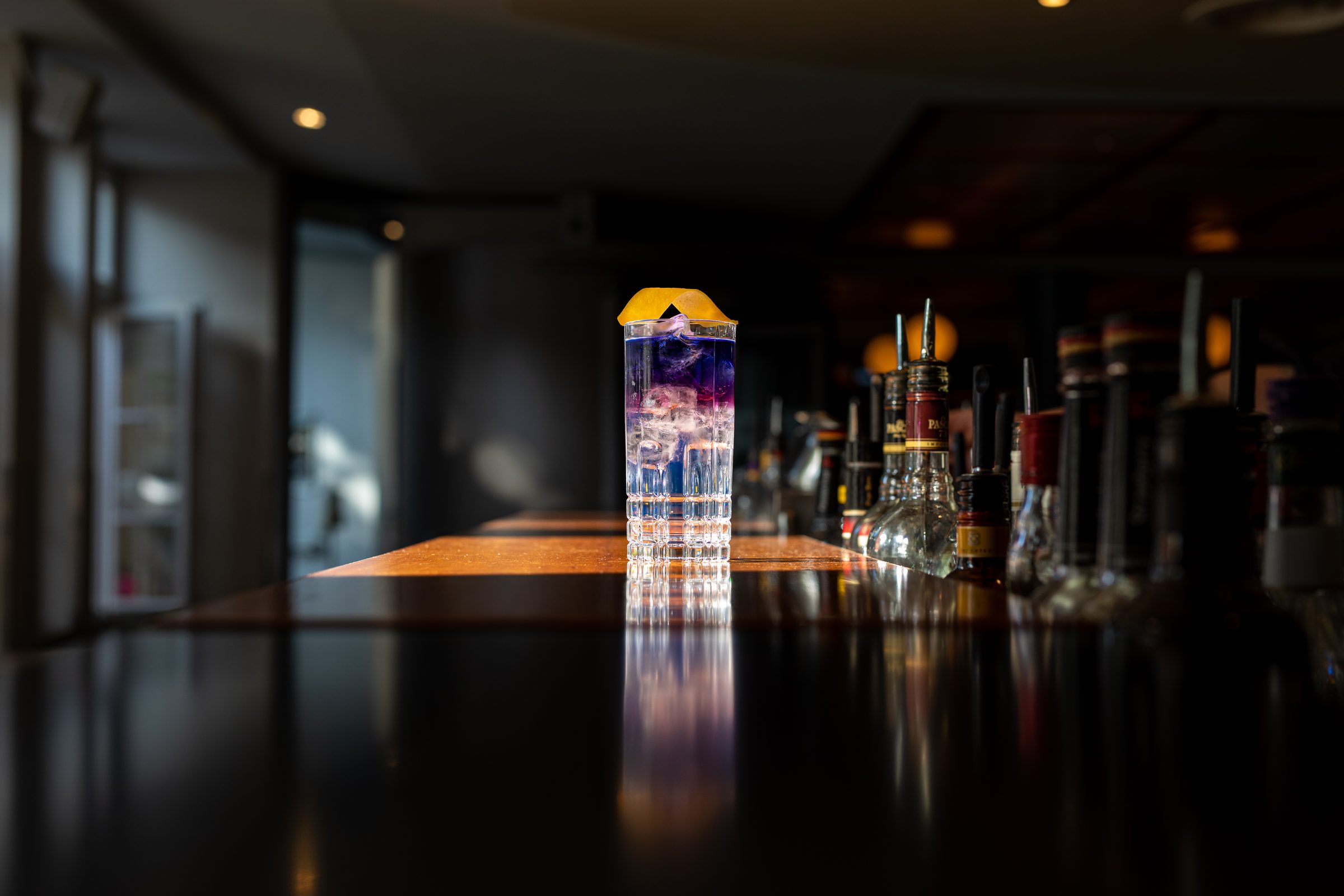 Violett geschichteter Longdrink auf dem spiegelnden Tresen der abendlich dunklen Bar des Ludwig in Mosbach