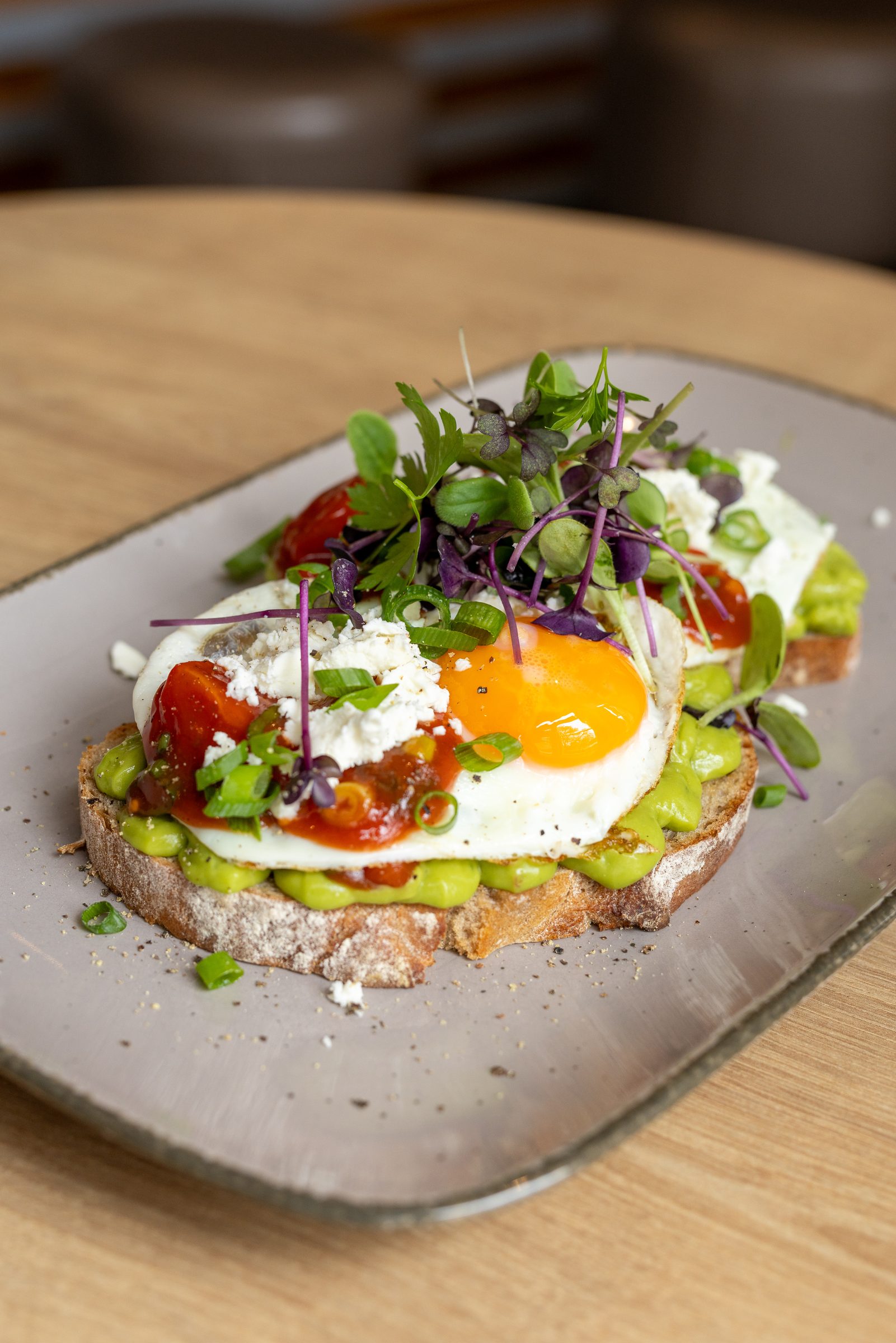 Brot mit Avocado, Spiegelei, Tomaten, Feta und Sprossen auf einem grauen Teller im Ludwig in Mosbach