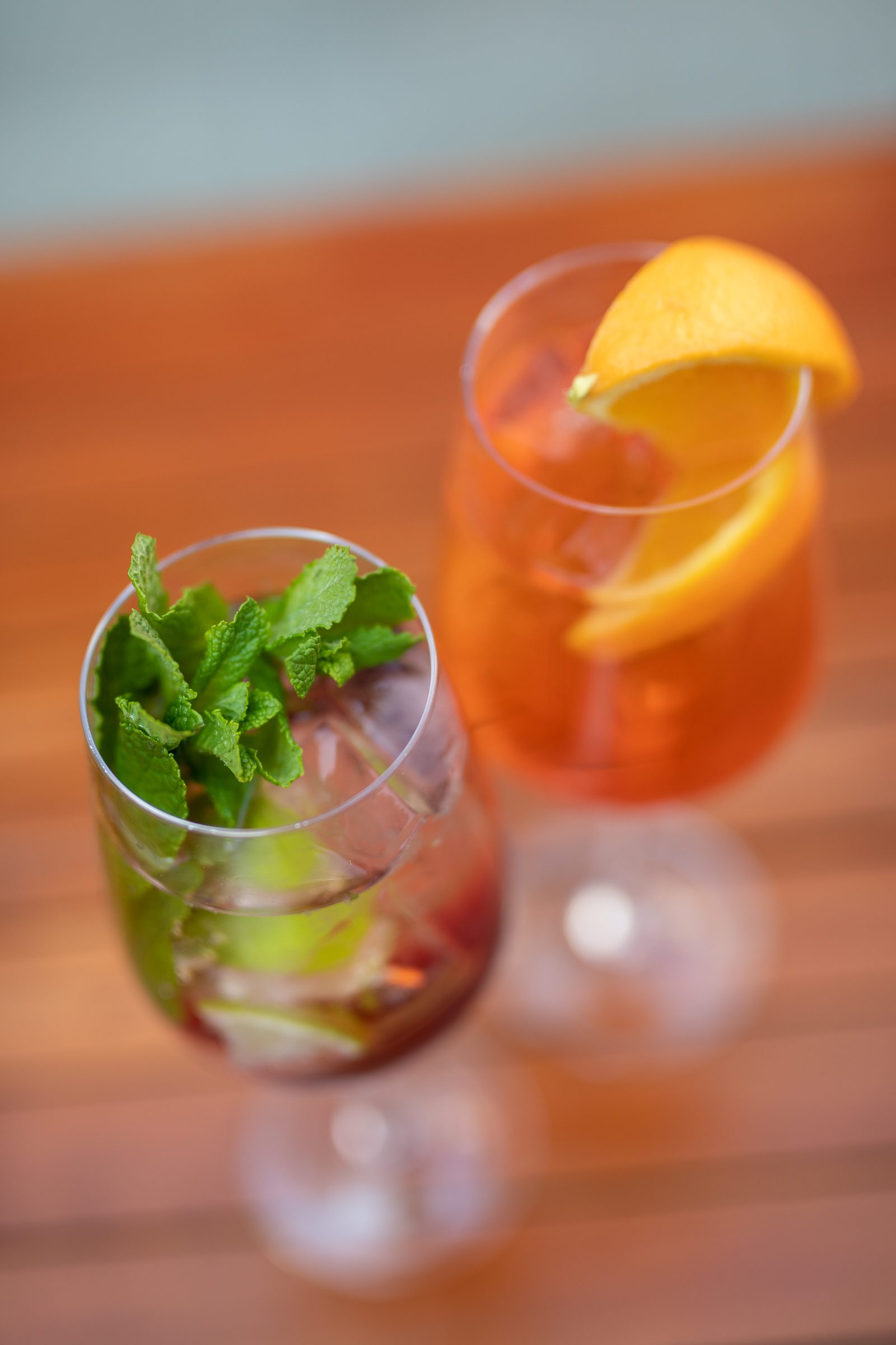 Spritz mit Orangenscheibe und ein Glas mit Minze auf einem Holztisch im Freien beim Ludwig in Mosbach