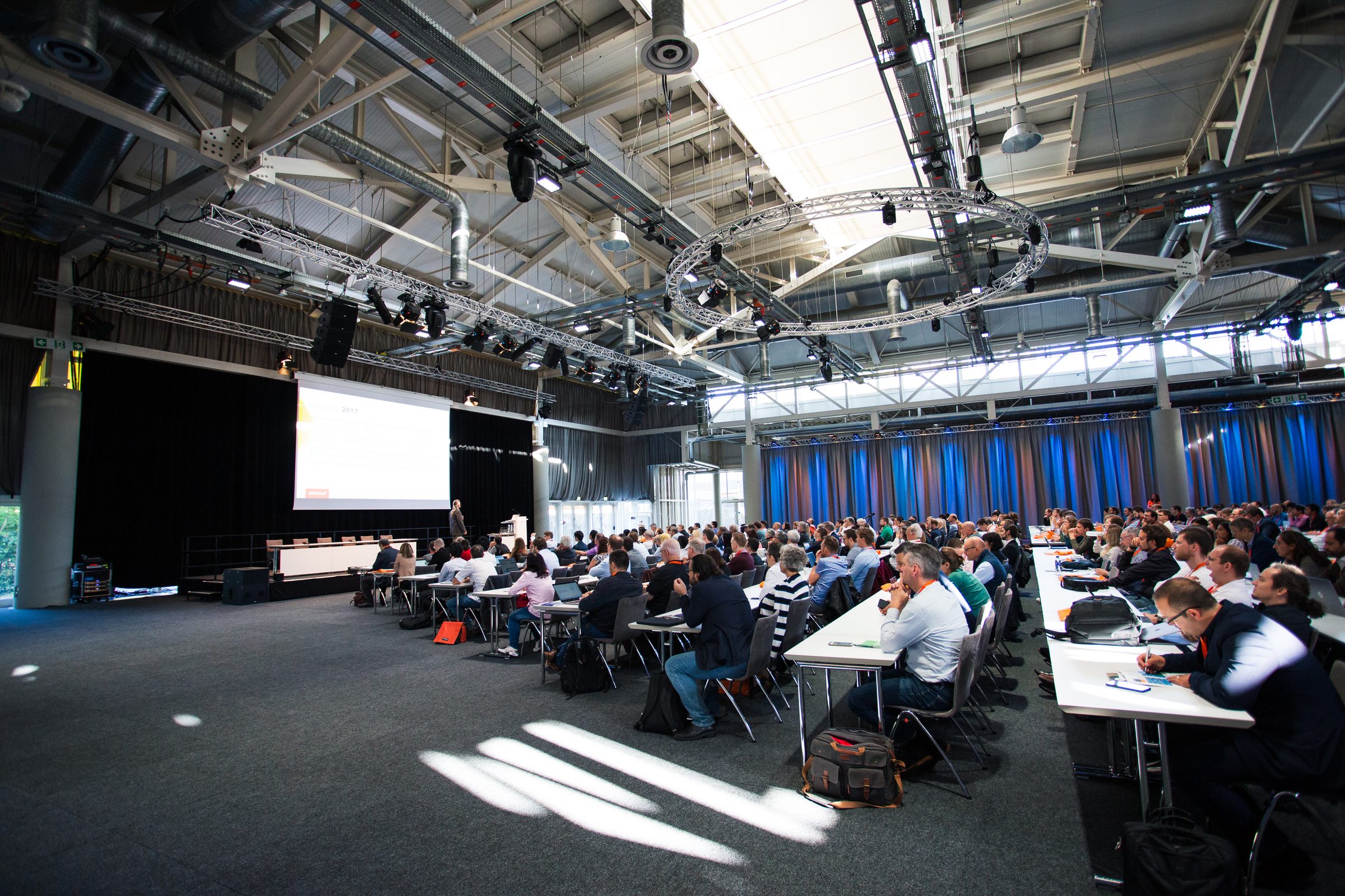 Voll besetzte Konferenzhalle mit Publikum an Tischreihen und einem Vortrag auf der Bühne bei der Semantics