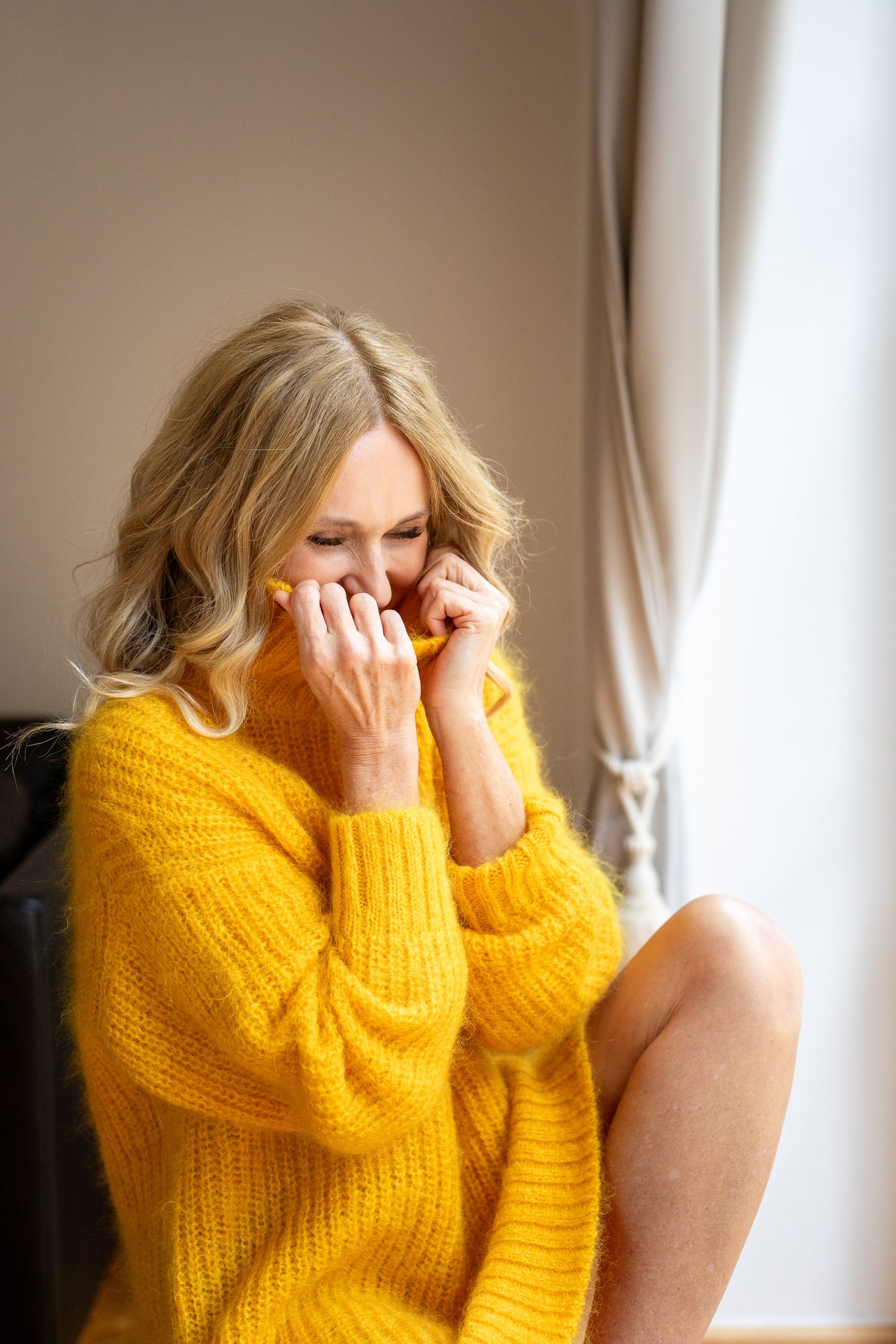 Nowshine lacht und zieht den Kragen ihres gelben Strickpullovers bis ans Gesicht