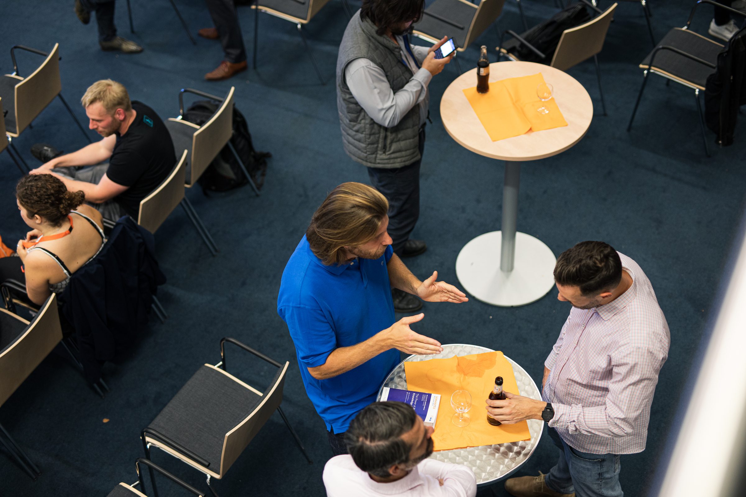 Blick von oben auf Teilnehmende der Konferenz SEMANTiCS, die sich beim Meetup an Stehtischen unterhalten