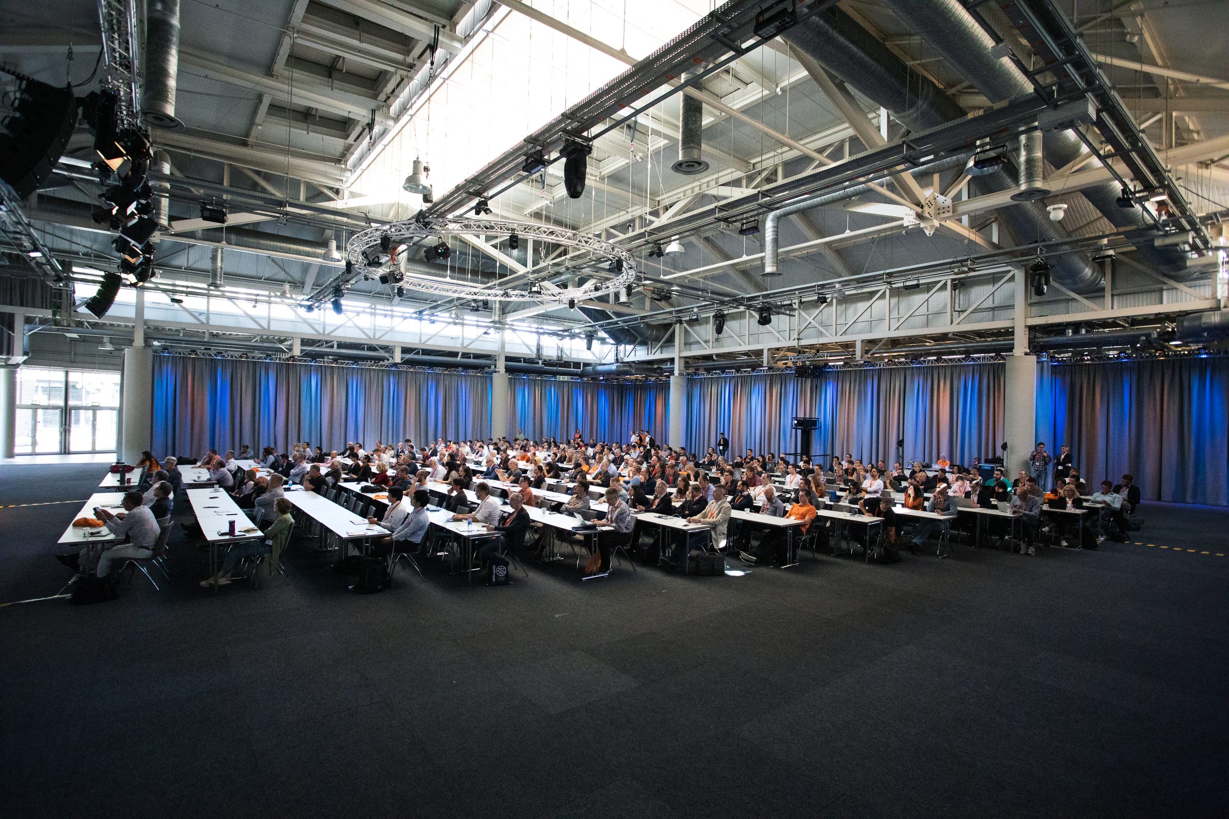 Weitwinkelblick in die große Halle der Konferenz SEMANTiCS mit voll besetzten Tischreihen vor blauen Vorhängen