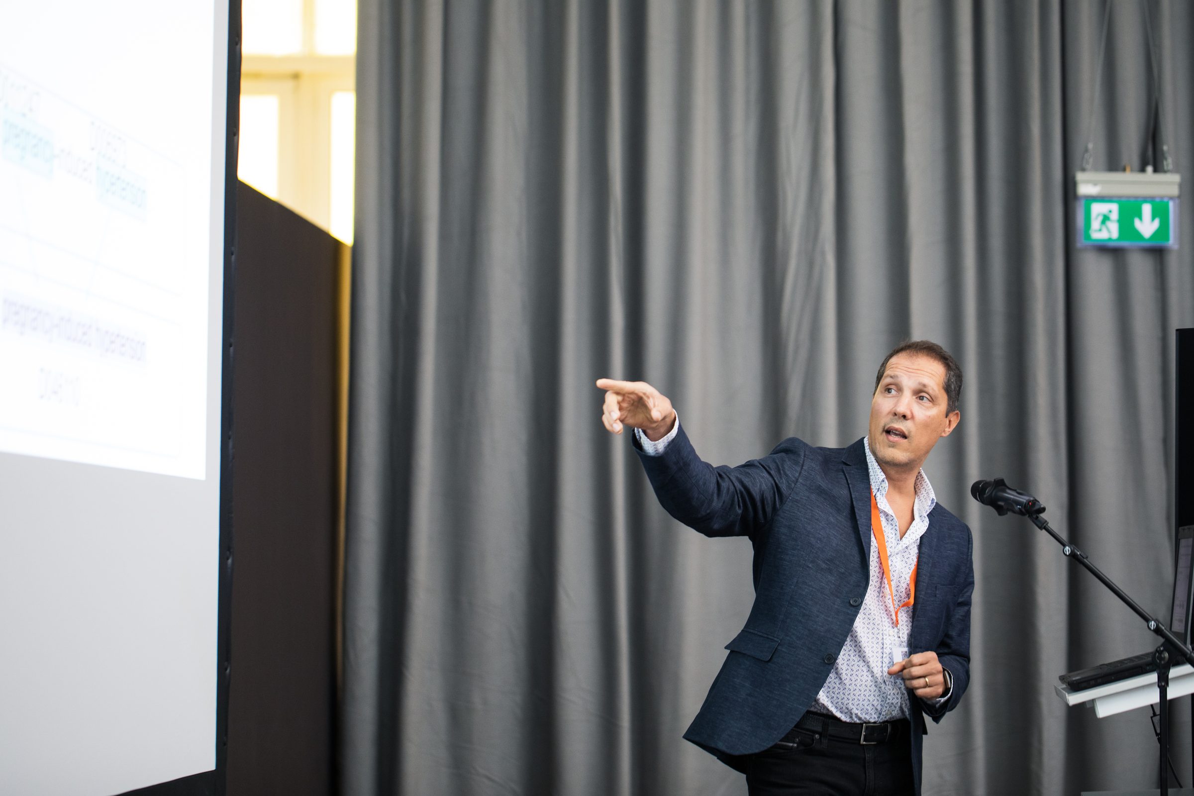 Redner zeigt neben dem Rednerpult auf seine Präsentation bei einem Vortrag auf der Konferenz SEMANTiCS
