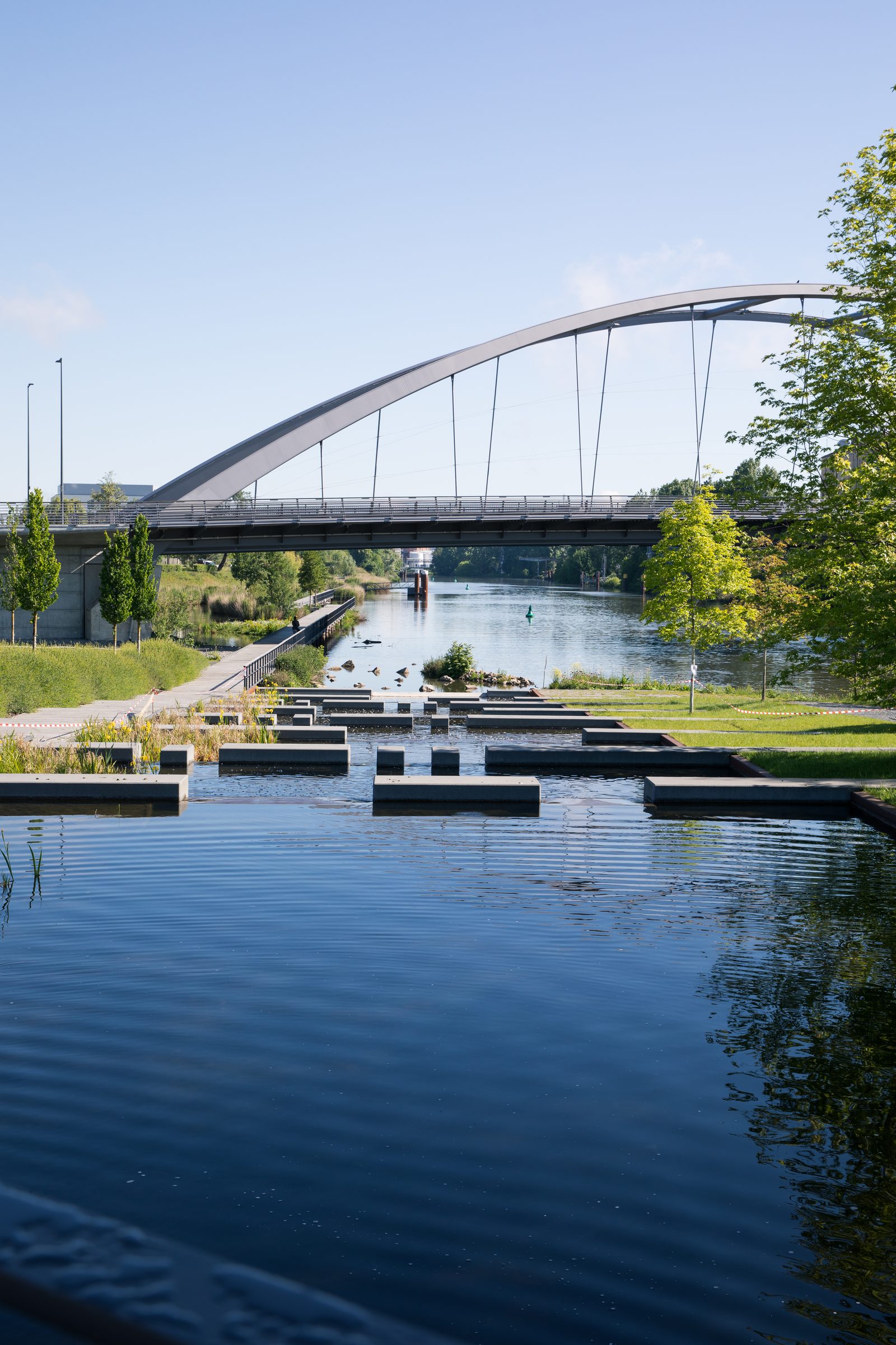 Bogenbrücke über den Neckar in Heilbronn, davor Wasserbecken und Stufen am Ufer