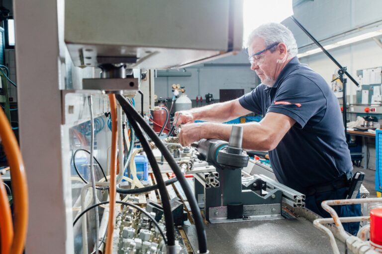 Mitarbeiter mit Schutzbrille montiert einen Hydraulikzylinder in der Fertigung von Weber Hydraulik