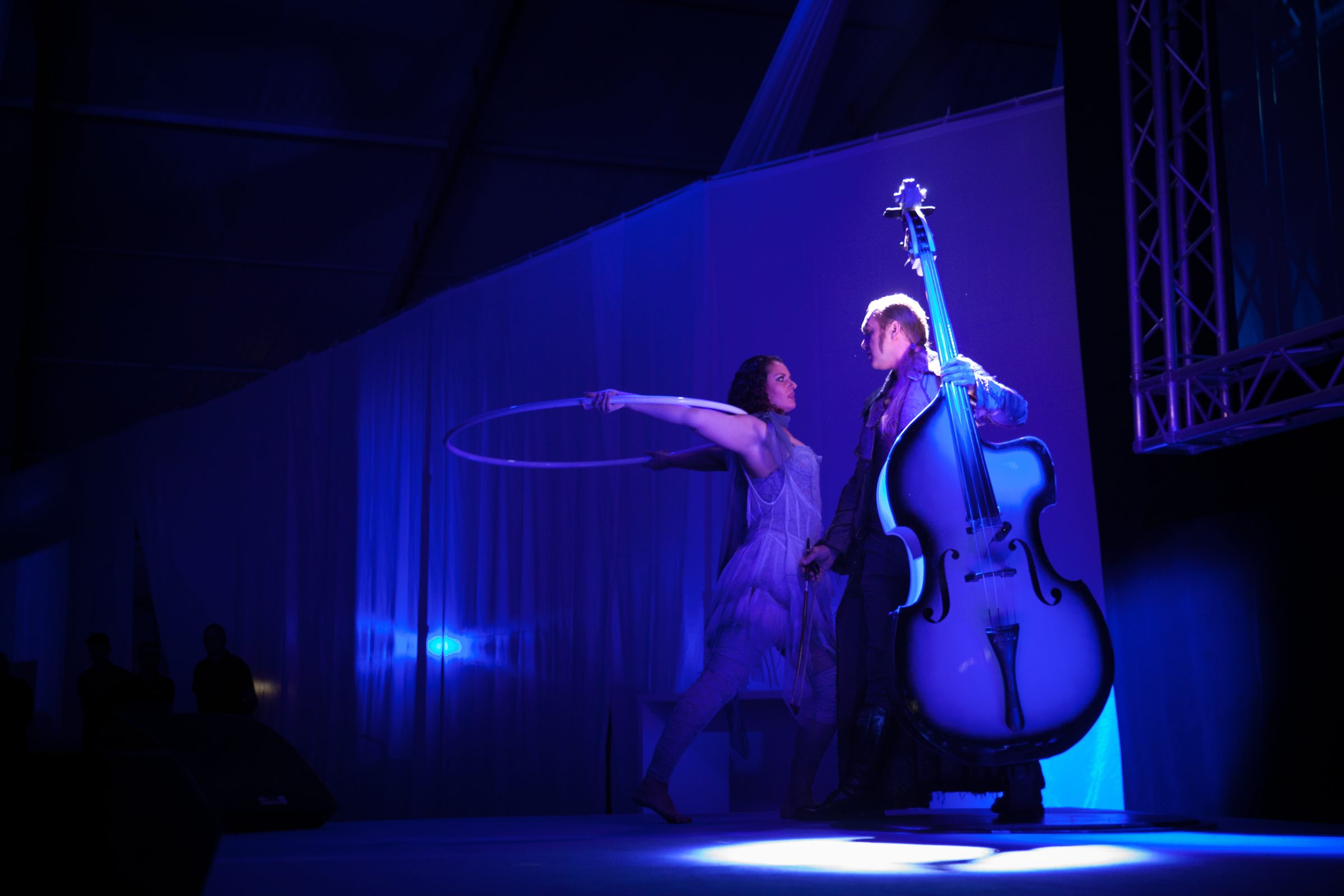 Musikerin mit Kontrabass und Artistin mit Reifen in blauem Licht auf der Bühne beim Firmenjubiläum von Weber Hydraulik
