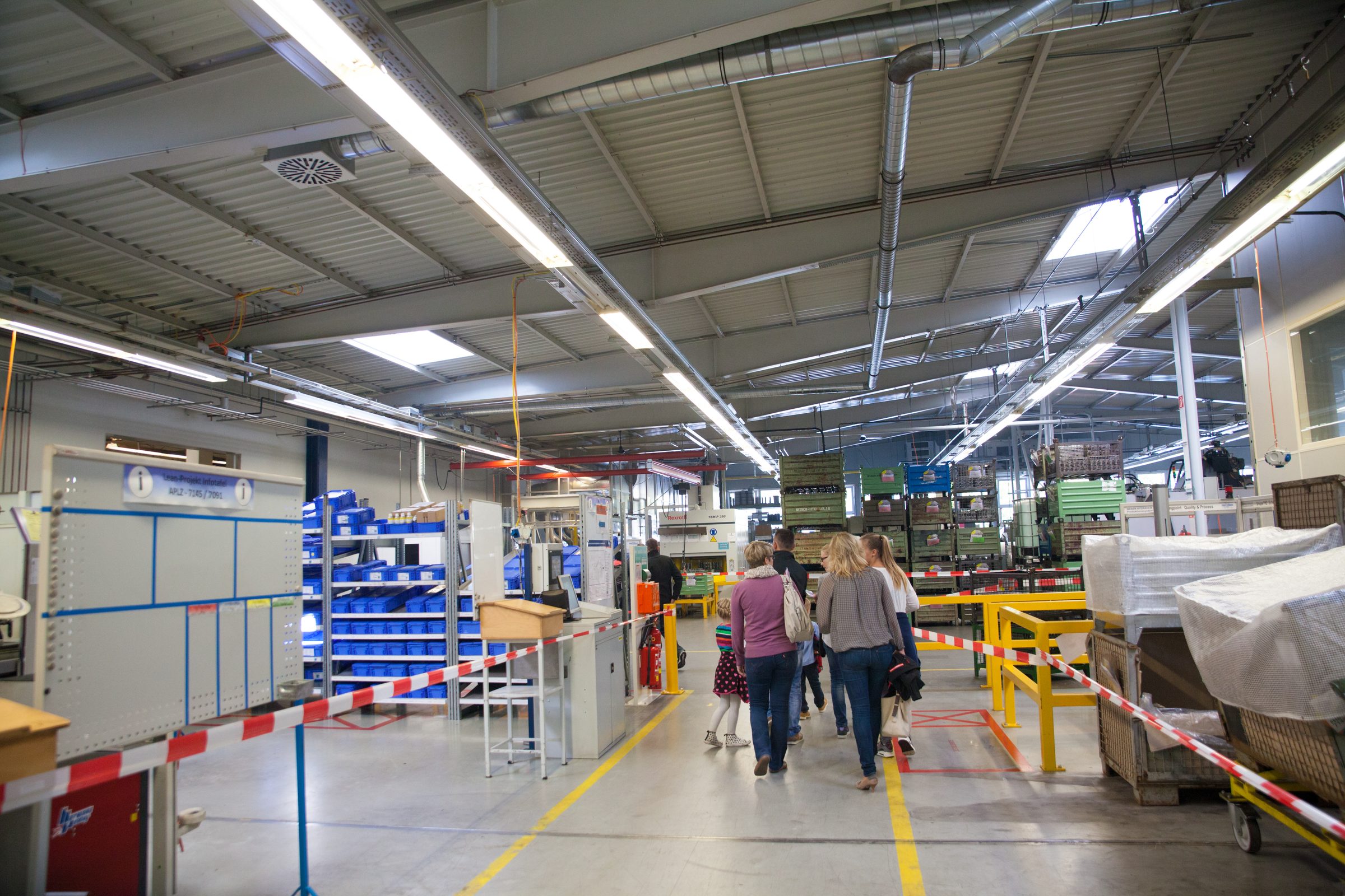 Besucherinnen und Besucher mit Kindern gehen beim Firmenjubiläum durch eine Fertigungshalle von Weber Hydraulik