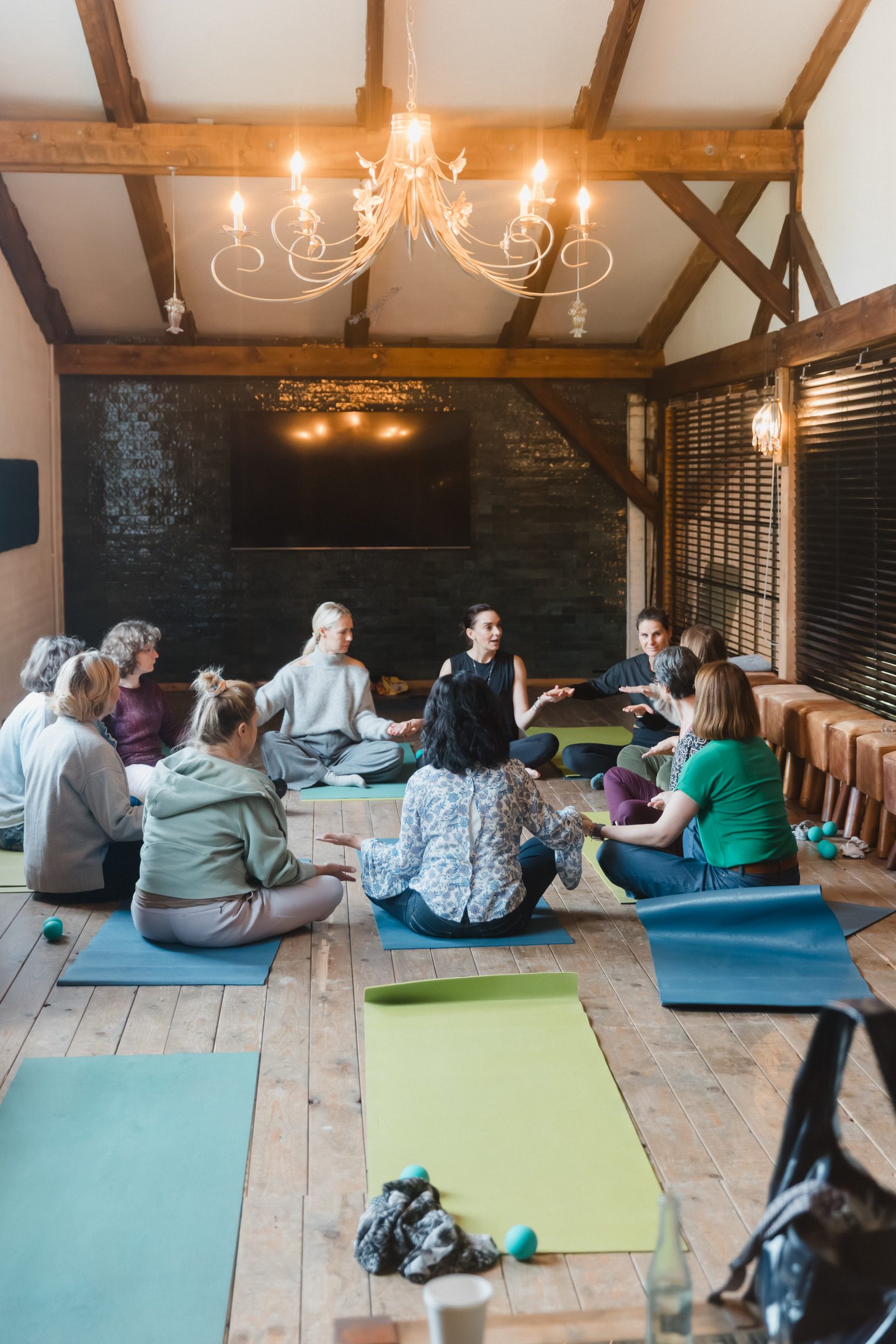 Yoga-Workshop beim Pro Age Event von XbyX, Frauen sitzen im Kreis auf bunten Matten unter einem Kronleuchter