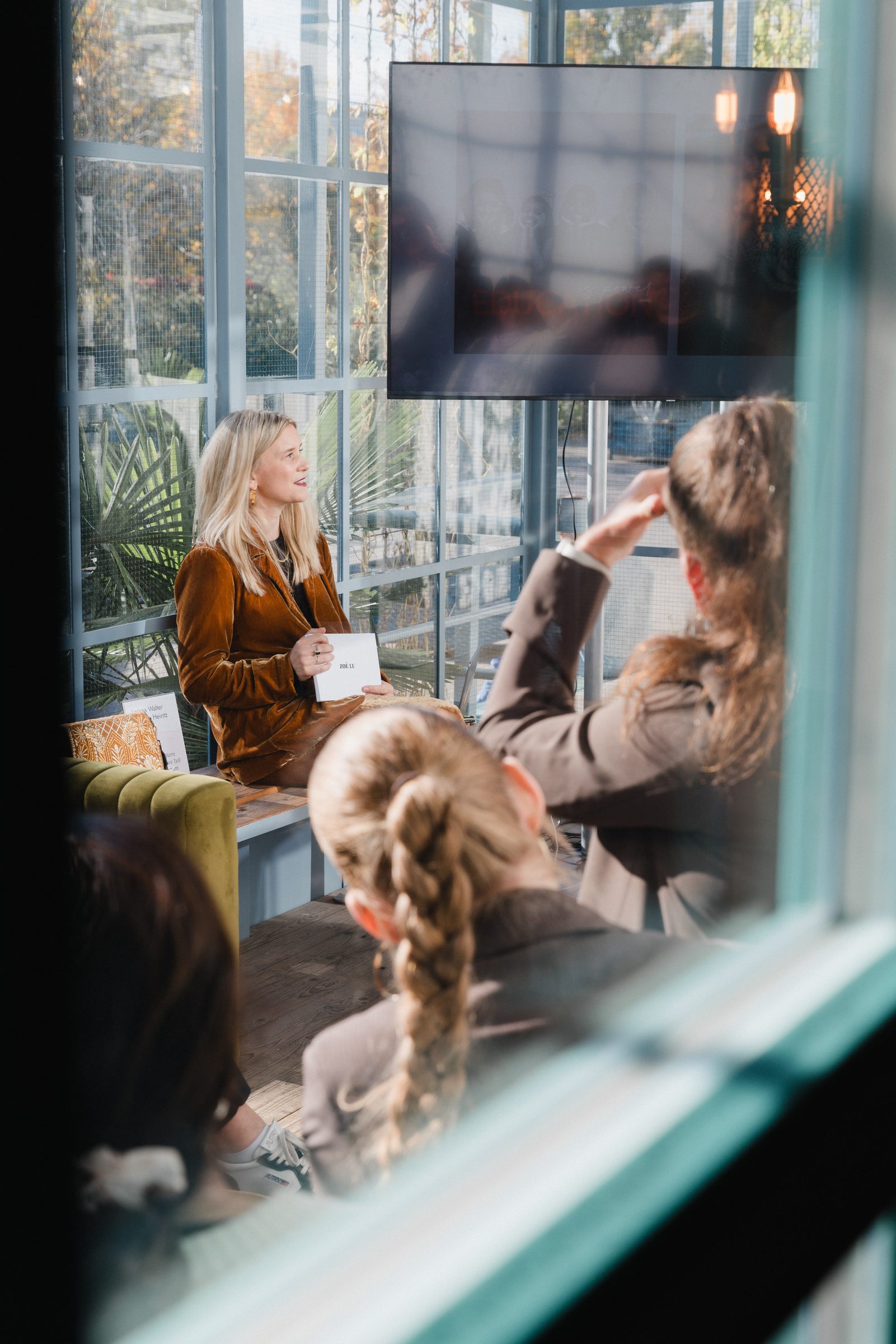 Blick durch ein Fenster auf eine Gesprächsrunde im Wintergarten beim Pro Age Event von XbyX
