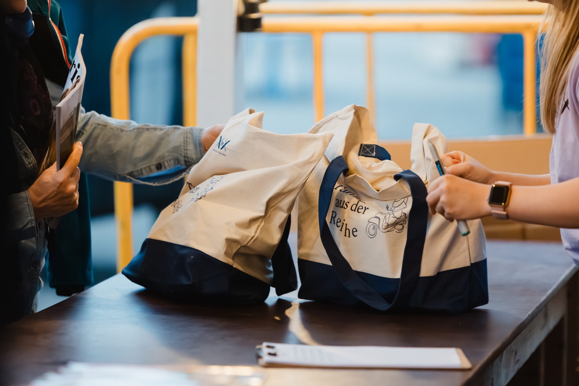 Gäste nehmen am Empfang beim Pro Age Event von XbyX Stofftaschen entgegen